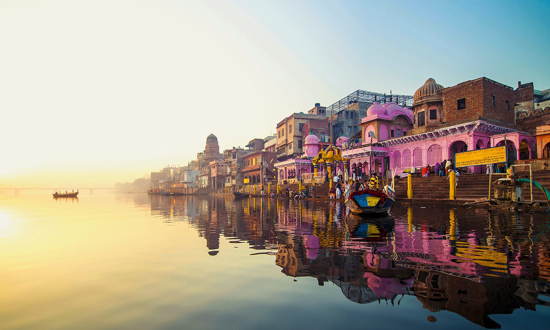 Sunrise over the sacred ghats and temple steps beside still river water in India