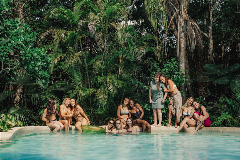 Retreat guests gathered at the edge of a turquoise jungle cenote at DORA Jungle, Tulum