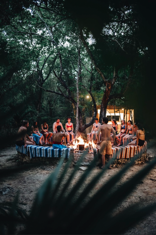 Evening fire circle ceremony with retreat guests gathered in the DORA Jungle